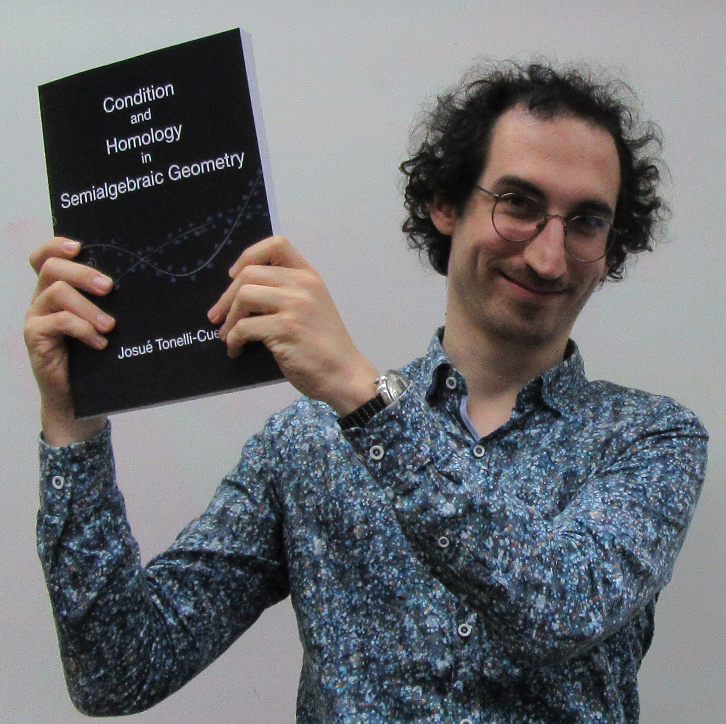 Josué Tonelli Cueto sosteniendo una copia de su tesis doctoral
